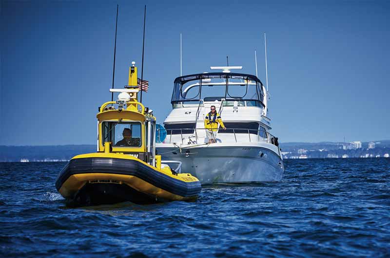 Sea Tow boat towing a large yacht with a man on front deck