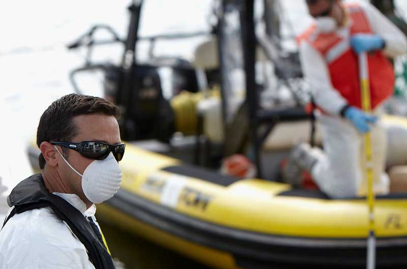 man in facemask performing environment al cleanup work