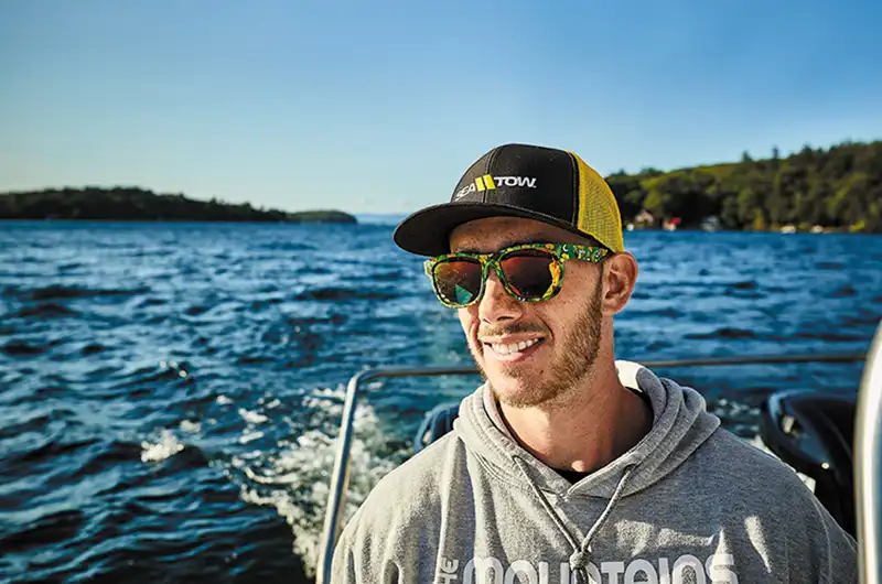 sea tow member wearing black/yellow mesh hat driving his boat