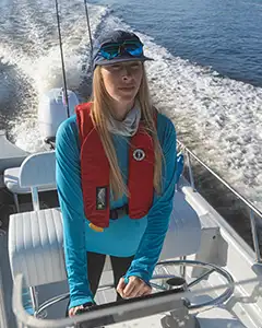 woman driving boat wearing mustang survival life jacket
